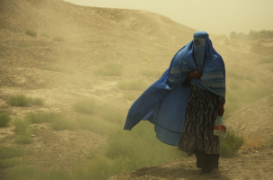 The photo shows a woman with burqa in a little sandstorm, near of Balkh. <br/>Wikimedia Commons