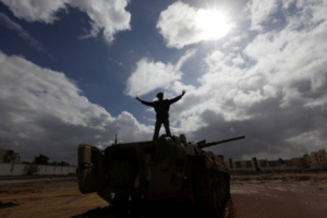A Libyan man flashes the V sign as he stands over a destroyed tank at the Al-Katiba military base which fell to protesters against Moammar Gaddafi in Benghazi <br/>AP