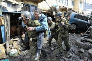 A man who's been stranded in a residence is carried on the back of a Japanese soldier to higher grounds at Kesennuma, northeastern Japan, on Saturday March 12, 2011, one day after a giant quake and tsunami struck the country's northeastern coast. <br/>AP/Kyodo News