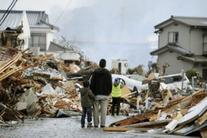 A father and child who lost their home stand in front of debris in Sendai, northern Japan Saturday, March 12, 2011 after Japan's biggest recorded earthquake slammed into its eastern coast Friday. <br/>