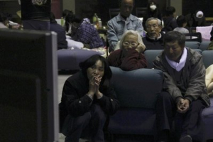 Evacuees watch news on a troubled nuclear power plant on television at a makeshift shelter in Fukushima, northern Japan, Tuesday, March 15, 2011, four days after a powerful earthquake-triggered tsunami hit the country's east coast. <br/> AP/The Yomiuri Shimbun, Koichi Nakamura