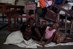 A woman with two of her children rest on the floor at the shelter set up in the Lycee Philippe Guerrier ahead of Hurricane Matthew in Les Cayes, Haiti.<br />
 <br/>Reuters