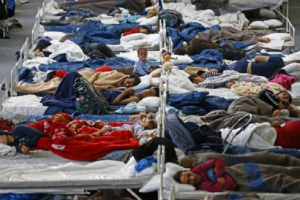 Migrants rest on beds at an improvised temporary shelter in a sports hall in Hanau, Germany September 22, 2015.  <br/>Reuters/Kai Pfaffenbach