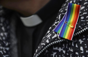 A priest wears a rainbow ribbon during a vigil against Anglican Homophobia, outside the General Synod of the Church of England in London, Britain, February 15, 2017.  <br/>REUTERS/Hannah McKay
