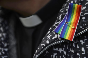 A priest wears a rainbow ribbon during a vigil against Anglican Homophobia, outside the General Synod of the Church of England in London, Britain, February 15, 2017.  <br/>REUTERS/Hannah McKay
