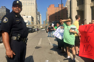 Detroit Police Captain Darrell Patterson stands between deportation protesters and traffic in downtown Detroit, Michigan. <br/>Detroit Free Press/Allie Gross.