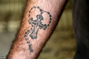 A fighter from the Syriac Military Council, a Christian militia fighting alongside the Syrian Democratic Forces against the Islamic State (IS) group in Raqa, shows his tattoo of a cross and rosary beads <br/>AFP