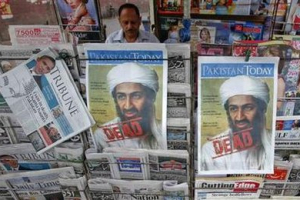 A roadside vendor sells newspapers with headlines about the death of al-Qaida leader Osama bin Laden, in Lahore May 3, 2011. <br/>Reuters / Mohsin Raza