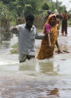 A man helps a woman cross a flooded road at Manikganj, 70km (44 miles) from the capital Dhaka, August 3, 2007. More than 200 people have died in monsoon flooding in South Asia in the last 10 days while more than 10 million remained marooned in their villages or homeless on Friday, with many having no access to health care. <br/>(Photo Reuters/Rafiqur Rahman)