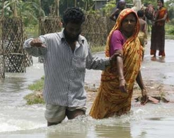 A man helps a woman cross a flooded road at Manikganj, 70km (44 miles) from the capital Dhaka, August 3, 2007. More than 200 people have died in monsoon flooding in South Asia in the last 10 days while more than 10 million remained marooned in their villages or homeless on Friday, with many having no access to health care. <br/>(Photo Reuters/Rafiqur Rahman)