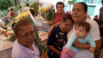Facunda Villanueva Perez, 67, whose sister was among the 11 killed at the Atzala church in Mexico, holds her grandchild and mourns with relatives at the victims' wake Wednesday.  <br/>LA Times
