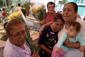 Facunda Villanueva Perez, 67, whose sister was among the 11 killed at the Atzala church in Mexico, holds her grandchild and mourns with relatives at the victims' wake Wednesday.  <br/>LA Times