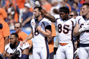 Denver Broncos tight end Virgil Green (85) raises his fist in protest as teammate Max Garcia, left, takes a knee during the national anthem. <br/>Getty Images
