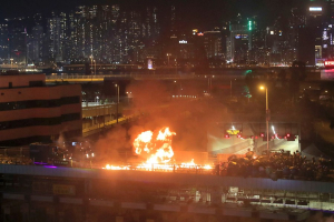 Protestors hurl Molotov cocktails as armored police vehicles approach their barricades on a bridge over a highway leading to the Cross Harbour Tunnel in Hong Kong on Sunday, Nov. 17, 2019.<br />
 <br/>KIN CHEUNG/AP