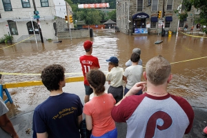 Residents of Manayunk, a suburb of Philadelphia watch as the flooded Schuylkill River covers Main Street following Hurricane Irene August 28, 2011. Hurricane Irene was downgraded to a tropical storm on Sunday morning after marching up the East Coast, leaving 11 dead, as many as 3.6 million customers without electricity, forcing the closure of New York's mass transit system, and the cancellation of thousands of flights. <br/>REUTERS/Jason Reed