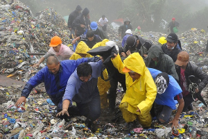 Rescuers and volunteers carry the body of a victim from tonnes of garbage piled up after the retaining wall of a dumpsite collapsed, killing four people and damaging several houses at the height of Typhoon Nanmadol, locally known as Typhoon Mina, in Baguio City, north of Manila, August 29, 2011. Nanmadol hit the northern Philippines late last week, killing 12 and injuring 21, the country's national disaster council said on Monday. <br/>Rescuers and volunteers carry the body of a victim from tonnes of garbage piled up after the retaini