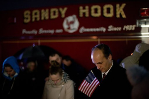 Mourners listen to a memorial service over a loudspeaker outside Newtown High School for the victims of the Sandy Hook Elementary School shooting, Sunday, Dec. 16, 2012, in Newtown, Conn. <br/>David Goldman /AP Photo 