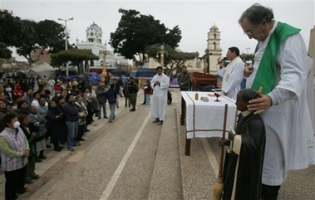 Catholic priest Alfonso Berrade, right, places his hand on the head of a representation of Peruvian saint San Martin de Porres while attending mass at the main square in Pisco, Peru, Sunday, Aug. 19, 2007. Berrade is the head of the San Clemente church which collapsed killing more than a hundred faithful during the earthquake that shook the southern coast of Peru Aug. 15. <br/>(Photo: AP Images / Martin Mejia)