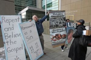 passerby, right, pauses as William Whatcott (facing at left) protests homosexuality and abortion in 2009. <br/>Ted Jacob/Postmedia New