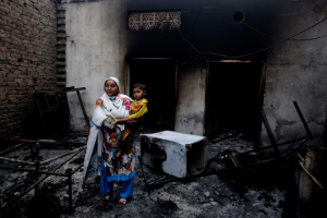 A Pakistani Christian woman holding her son stands among the rubble of their home damaged by an angry Muslim mob in Lahore, Pakistan, on March 10, 2013 <br/>K.M. CHAUDARY / AP