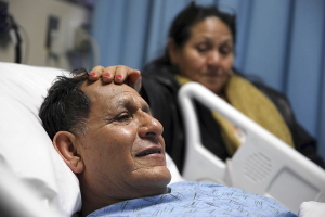 Luis Quizhpe, owner of Quizhpe's Gifts and Sports in Logan Square, is comforted by his wife, Aida, on Wednesday while he recovers in a North Side hospital from a gunshot wound. Quizhpe was shot during a robbery Tuesday at his store. <br/>Scott Strazzante, Chicago Tribune / April 10, 2013
