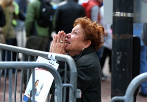 Looking to heaven: A woman kneels and prays at the scene of the first explosion in Boylston Street as the city comes to terms with the atrocity. <br/>Boston Globe
