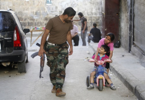 A member of the Free Syrian Army interacts with children in Aleppo's Karm al-Jabal district, June 6, 2013. <br/>REUTERS/Muzaffar Salman