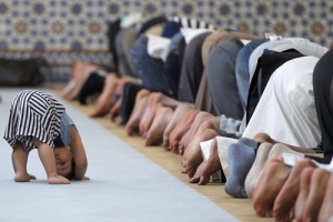 A child is seen near members of the Muslim community attending midday prayers at Strasbourg Grand Mosque in Strasbourg on the first day of Ramadan July 9, 2013.  <br/>REUTERS/Vincent Kessler 