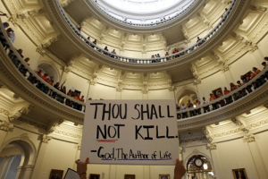 An anti-abortion protester holds a placard as protesters line the railing on the second floor of the rotunda of the State Capitol as the state Senate meets to consider legislation restricting abortion rights in Austin, Texas July 12, 2013. Texas on Friday is poised to enact a ban on most abortions after 20 weeks of pregnancy, ending a bitter political fight that stirred national debate over what critics see as laws threatening the right to abortion in the United States. <br/>REUTERS/Mike Stone 