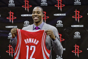 Newly signed Houston Rockets player Dwight Howard holds up his new team jersey during a news conference in Houston, Texas July 13, 2013 <br/>Reuters