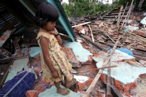 A local girl pauses at her house destroyed by earthquake in Bengkulu, Sumatra island, Indonesia, Thursday, Sept. 13, 2007. Three powerful earthquakes jolted Indonesia in less than 24 hours, triggering tsunami warnings, damaging hundreds of houses and sending panicked residents fleeing to high ground. Rescuers feared some victims were trapped beneath the rubble. <br/>(Photo: AP Images / Dita Alangkara)