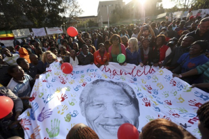 Well-wishers hold a giant banner with an image of former South African President Nelson Mandela as they gather to wish him a happy birthday outside the Medi-Clinic Heart Hospital, where he is being treated, in Pretoria July 18, 2013. Anti-apartheid hero Mandela is 'steadily improving', South Africa's government said on Thursday as the former president celebrated his 95th birthday in hospital amid tributes from around the country and the world. The Nobel Peace Prize laureate, globally admired as a symbol of struggle against injustice and of racial reconciliation, has been under treatment since June 8 for a recurring lung infection that has led to four hospital stays in the past six months. <br/>REUTERS/Siphiwe Sibeko