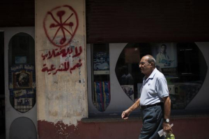 An Egyptian man walks in front of a pharmacy marked with anti-Coptic and anti-coup graffiti in Assiut, Upper Egypt. <br/>Photo: Manu Brabo, AP