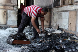 An Egyptian man clears the floor of charred objects in the Prince Tadros Coptic church which was set alight in Minya <br/>Giro Mais/EPA