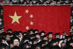 Graduates set next to the Chinese flag during a graduation ceremony at Fudan University in Shanghai June 28, 2013. A record high of 6.99 million students are expected to graduate from college this year which places severe pressure on their search for jobs, according to Xinhua News Agency. <br/>