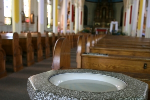 A stone font holding holy water at the back of the church. <br/>