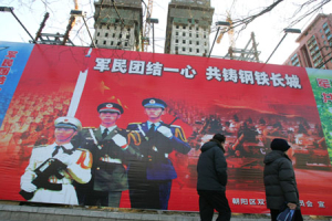 Pedestrians pass a billboard featuring images of the Chinese military on a Beijing sidewalk Wednesday Jan. 23, 2008. The slogan reads <br/>(Photo: AP Images / Greg Baker)