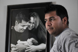 Erick Munoz stands before a photo of him and his wife, Marlise, after the birth of their first son, Mateo. (Photo: Courtesy of Munoz Family)<br />
<br />
 <br/>