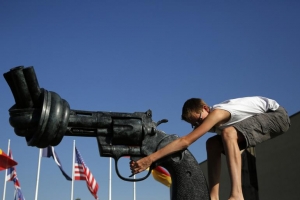 Every year, more than 7,000 U.S. children are hospitalized with gun-related injuries. Pictured, a teen plays on a bronze sculpture of a knotted gun entitled 