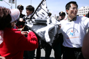 On Apr. 9, during the Torch Passing ceremony, rights activists (right) and China Olympic supporters (left) clashed against one another, where someone tried to grab the other’s sign. (Photo: The Gospel Herald/ Hudson Tsuei) <br/>Gospel Herald/ Hudson Tsuei