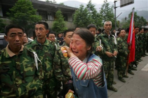 A woman cries as she walks by a line rescuers just before they are going to search for victims after the earthquake at Beichuan County in Mianyang of southwest China's Sichuan province, Tuesday, May 13, 2008. The official death toll after Monday's powerful 7.9 magnitude earthquake rose Tuesday to nearly 12,000, and thousands remained buried or missing. <br/>(Photo: AP Images / Color China) 