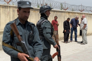 Afghan policemen keep watch as foreign nationals wait outside the Cure hospital in Kabul on April 24, 2014 <br/>Time