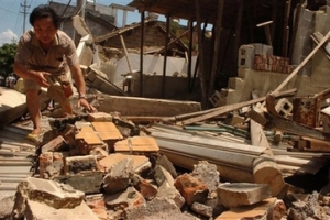 In this photo released by Xinhua News, Ren Baocun, a local resident, clears debris of his house after a strong earthquake shook the Yunnan Province on Sunday June 3, 2007. <br/>Xinhua, Qin Qing