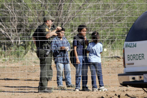 A Border Patrol agent stands at a ranch fence line with children taken into custody in southern Texas brush country north of Laredo. <br/>