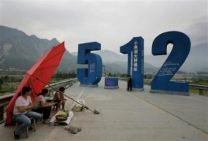 People rest beside a sculpture displayed to commemorate the date of the May 12 earthquake at the Xiaoyudong Bridge Site in Pengzhou of southwest China's Sichuan province Wednesday, Sep. 3, 2008. The site of the quake-damaged Xiaoyudong bridge is planned to be the center of the Longmenshan earthquake site park in Pengzhou. Over 80,000 people died in the May 12 earthquake which hit southwest China. <br/>(AP Photo/Color China Photo)