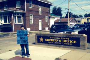 A member of New Beginnings Ministries holds a sign in front of the local sheriff's office protesting the arrest of pastor Bill Dunfee (Photo: Leonard Hayhurst/Tribune) <br/>