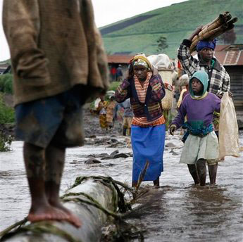 Residents of the eastern Congo village of Ngungu walk through high water Tuesday Nov. 11, 2008. A new front had opened Sunday Nov. 9, 2008 near Ngungu, some 50 km north west of Goma, where CNDP rebel forces fought Mai Mai forces allied with Congolese government troops. Tens of thousands have been displaced in the latest wave of fighting. <br/>(Photo: AP Images / Jerome Delay)