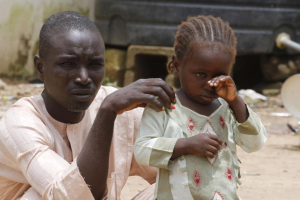 A girl rubs her eye beside her father in an internally displaced persons (IDP) camp, that was set up for Nigerians fleeing the violence committed against them by Boko Haram militants, at Wurojuli, Gombe State, September 1, 2014. CREDIT: REUTERS/SAMUEL INI <br/>