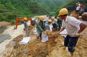 In this photo released by China's Xinhua News Agency, workers load sandbags to block flood waters at the Zoudong reservoir of Shuikou town, in Xingning city, in south China's Guangdong province, Monday, June 11, 2007. <br/>