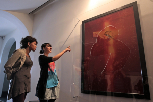 Visitors look at 'Piss Christ,' a piece of art by U.S. artist Andres Serrano, partially destroyed by catholic activists in Avignon, April 19, 2011. The Piss Christ created in 1987, is a photography representing a small plastic crucifix submerged in a glass of the artist's urine.  REUTERS/JEAN-PAUL PELISSIER <br/>